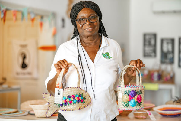 Artisan holding handmade straw handbags at the Middle Caicos Co-op store.