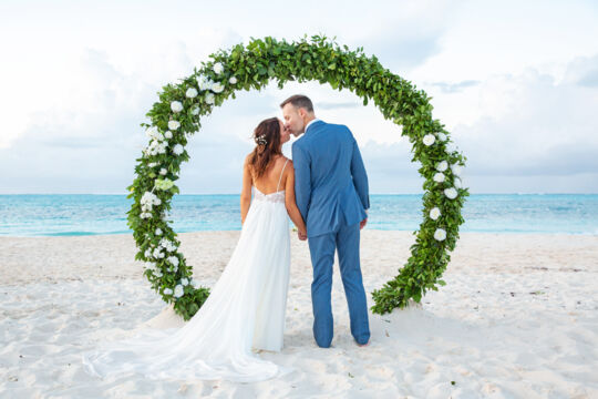 Married couple under a wedding arch on Grace Bay Beach. 