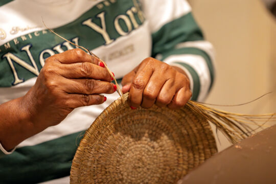 Woman stitching a fanner grass basket at the Middle Caicos Co-op, Turks and Caicos. 