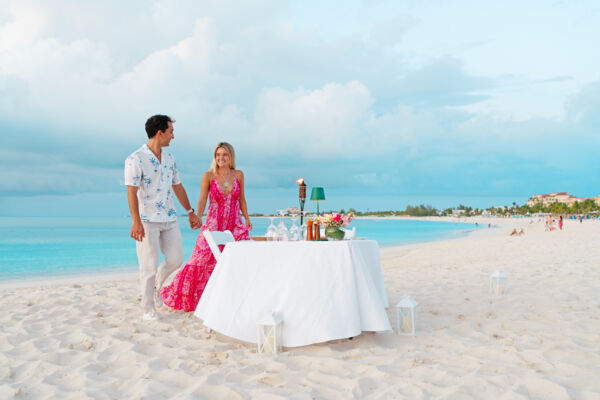 Couple at a table for two on beautiful Grace Bay at sunset. 