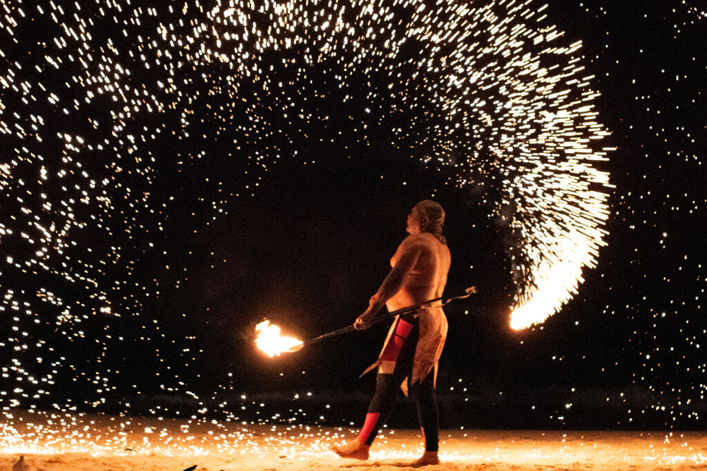 A fire dancer creates showers of sparks on Grace Bay Beach at night. 