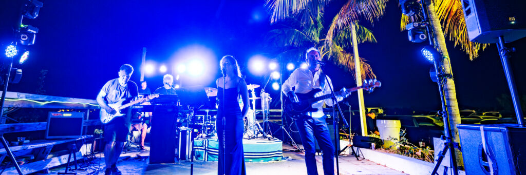 Rock band playing on an outdoor stage at night.