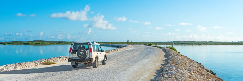 A white Land Rover Discovery vehicle driving across the causeway to Middle Caicos.