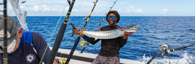 Man holding a large wahoo caught on a fishing charter. 
