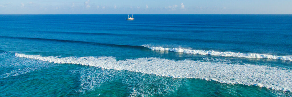 Rolling waves and the anchored Nero luxury yacht off the Grace Bay barrier reef