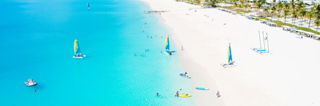 Aerial view of Hobie cat sailboats, paddle boards, and kayaks on Grace Bay Beach