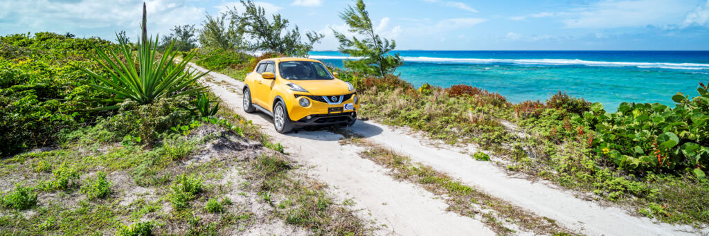 Yellow Nissan Juke driving down an ocean road in Turks and Caicos. 