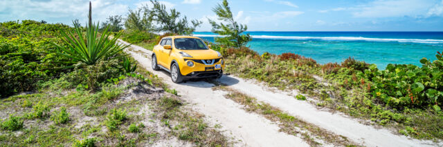 Yellow Nissan Juke driving down an ocean road in Turks and Caicos. 