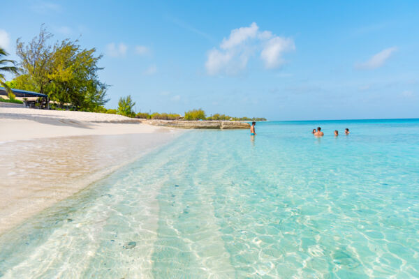 People swimming in shallow turquoise water at a beautiful beach