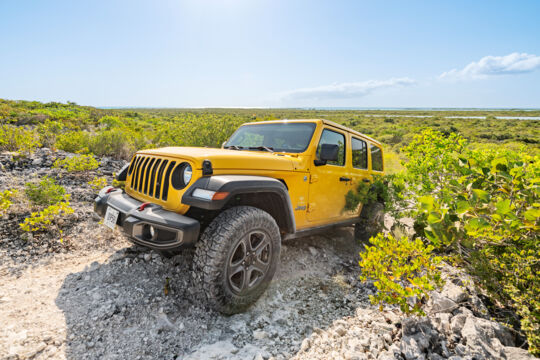 Yellow Jeep climbing a rocky incline in Turks and Caicos. 
