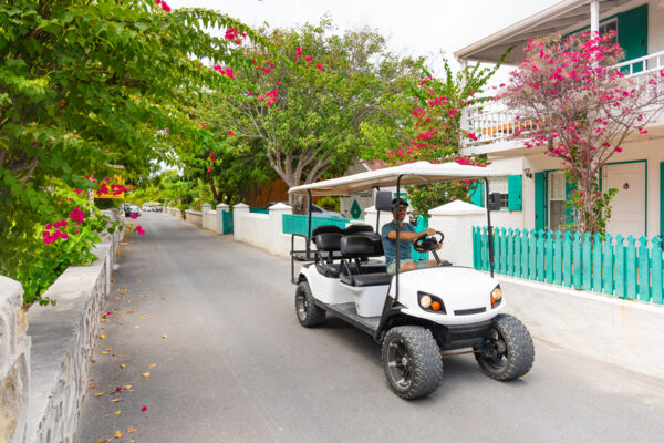 Man driving a golf cart down a historic street in Grand Turk
