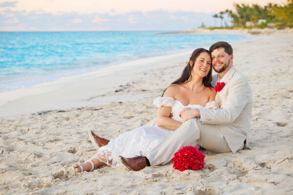 Newlyweds posing in the sand at a perfect beach.