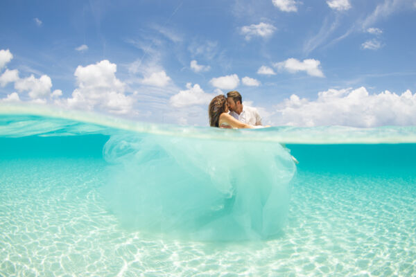 Newlyweds in turquoise ocean water.