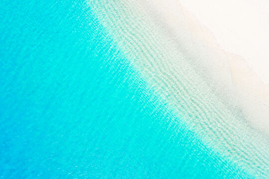 Overhead view of white sand and clear turquoise water of beach in the Turks and Caicos
