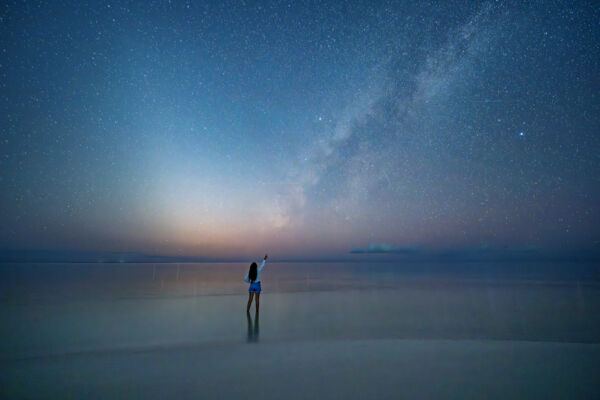 Person admiring a sky full of stars from the beach.