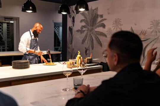 Chef torching a venison dish at a Turks and Caicos chef's table restaurant.