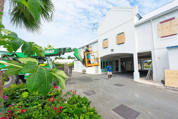 Workers using a telehandler to board up windows at a plaza to prepare for a hurricane.