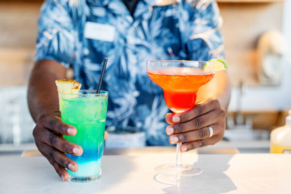 Bartender serving two colorful cocktails