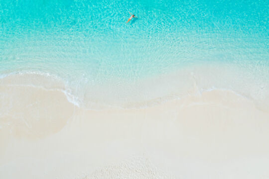 Child floating in crystal-clear turquoise water off Grace Bay Beach