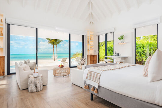 Luxury suite with floor-to-ceiling windows on a white-sand beach