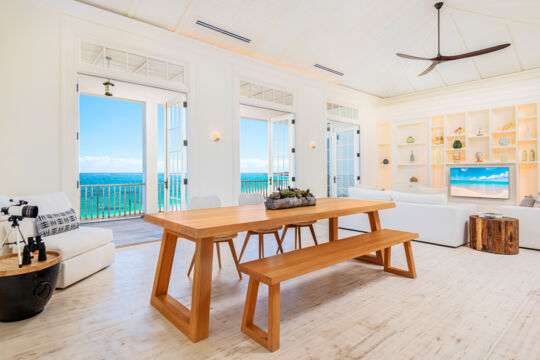 Dining table and living room with TV at villa overlooking the ocean