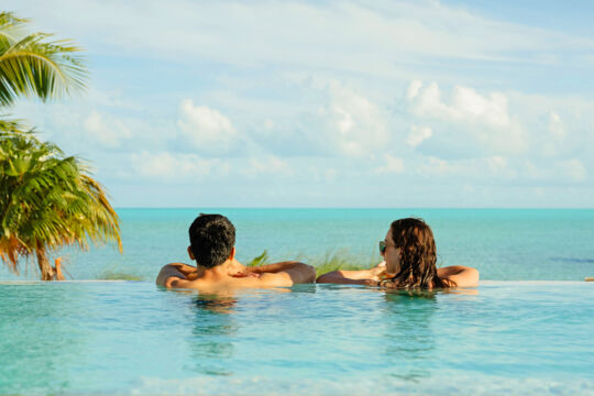 People in an infinity pool overlooking the ocean. 