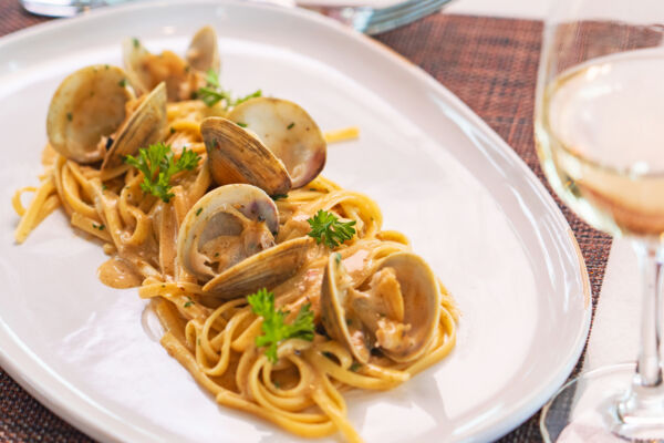 Pasta dish with clams and a glass of wine