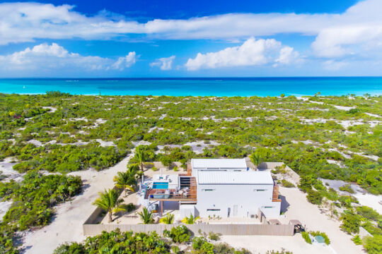 Aerial view of a villa located near a beach with turquoise water.
