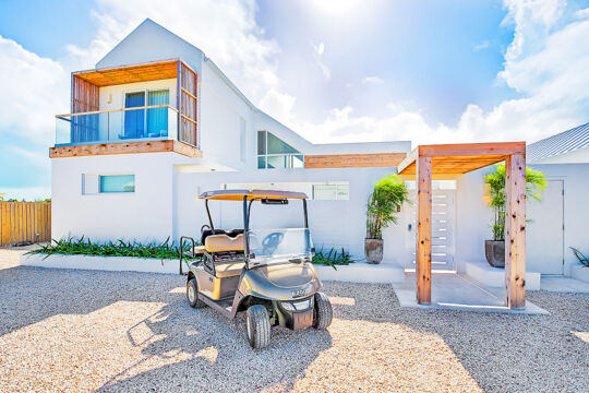 A golf cart parked in front of a luxury villa.