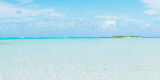 Shallow and clear ocean water at Bambarra Beach with Pelican Cay on the horizon