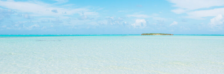Shallow and clear ocean water at Bambarra Beach with Pelican Cay on the horizon