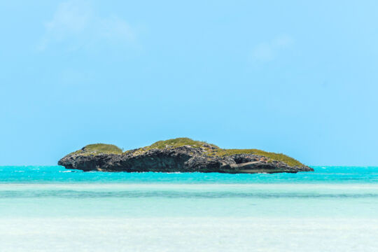 Rocky island with shrubbery, surrounded by turquoise water