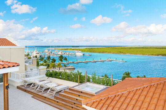 Penthouse terrace with pool loungers and a hot tub overlooking a marina