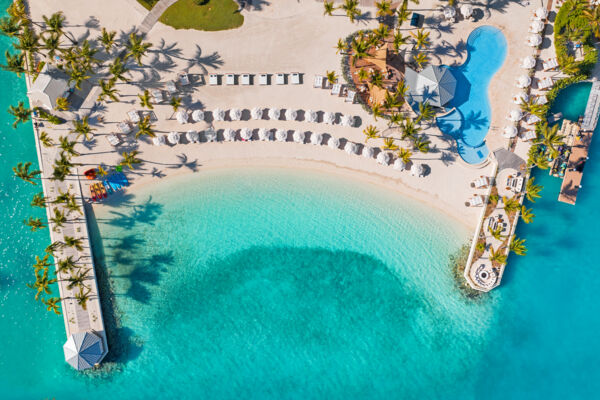 Overhead view of a resort pool and beach with turquoise water