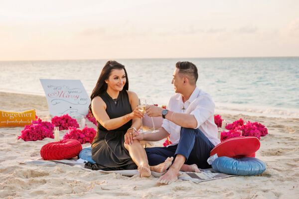 Newly engaged couple toasting champagne surrounded by flower petals on Grace Bay Beach