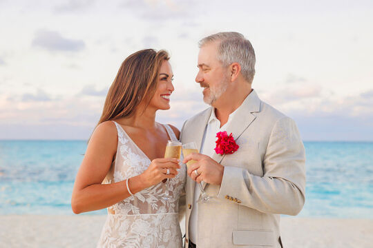 Newlyweds toasting on Grace Bay Beach at sunset.