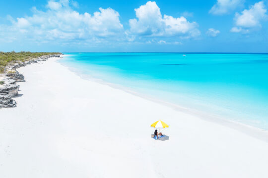 Aerial view of person and umbrella on a secluded beach at Water Cay.