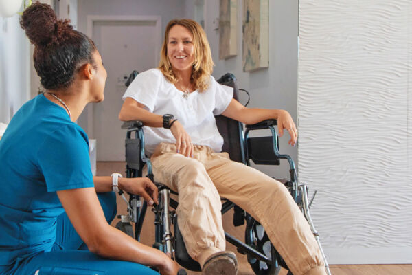 Nurse caring for a young woman in a wheelchair.