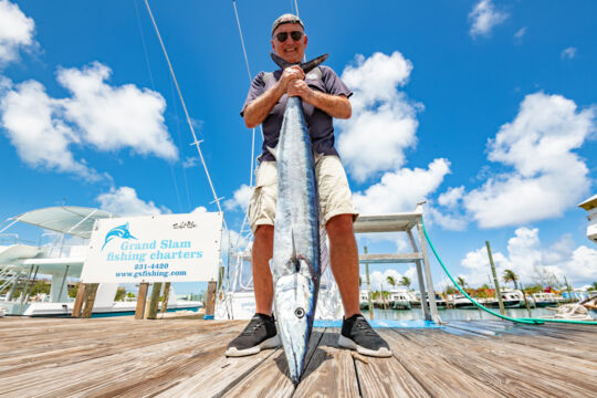 Man holding a large wahoo by the tail.