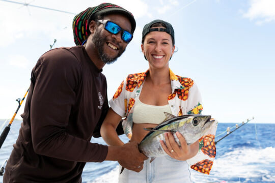 Woman holding blackfin tuna on fishing charter. 