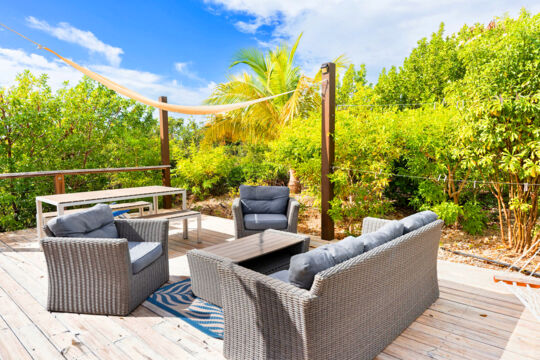 Patio armchair set and lush tropical trees at a villa. 