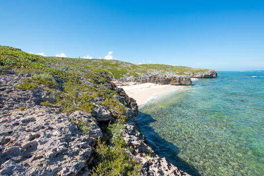 Coastal cliffs framing a beautiful beach at Highas Cay