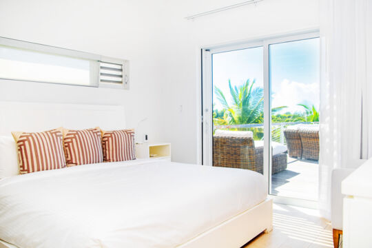 Modern white bedroom at a luxury villa with balcony view.