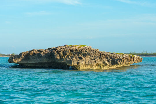 Tiny and porous rocky island of Inner Cay in the ocean