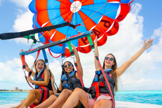 Three women attached to a parasail off Grace Bay Beach in Turks and Caicos