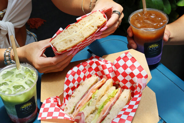 Two takeout sandwiches and iced coffees on a table