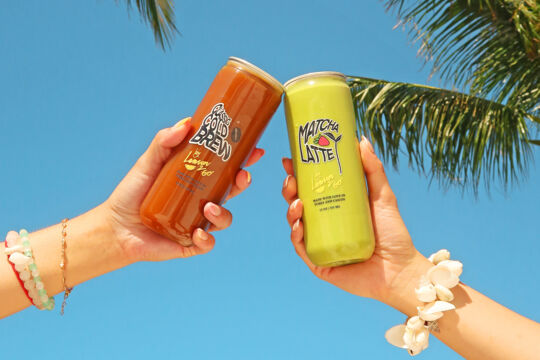 Hands holding a clear can of cold brew coffee and a clear can of matcha