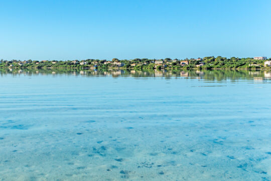 Houses on the coastline of a lagoon with flat calm water
