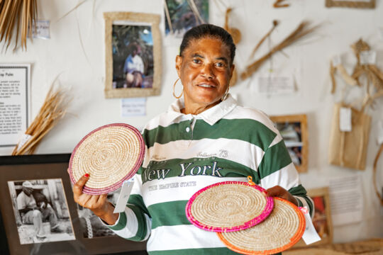 Woman holding straw placemats.