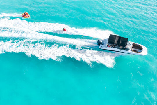 Speedboat pulling an inflatable tube across turquoise waters in Turks and Caicos. 